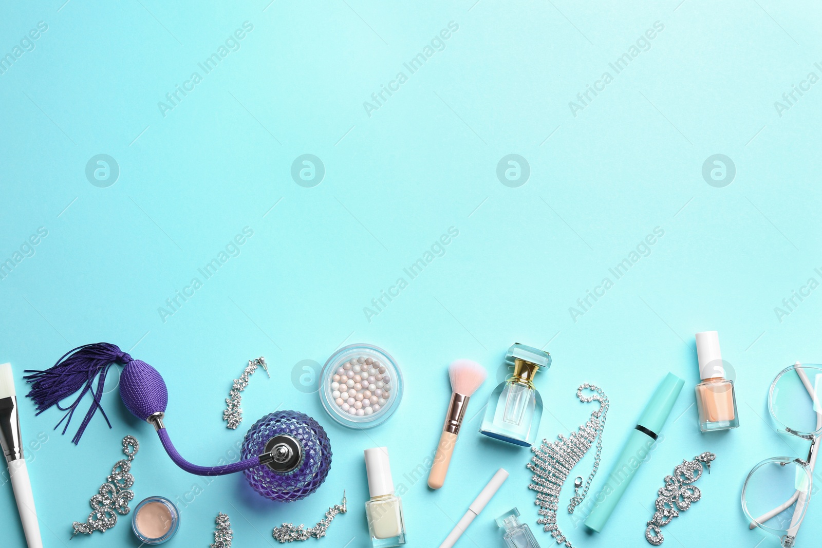 Photo of Flat lay composition with perfume bottles, jewelry and cosmetic products on light blue background, space for text