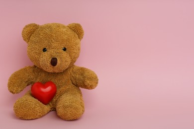 Photo of Cute teddy bear with red heart on pink background, space for text. Valentine's day celebration