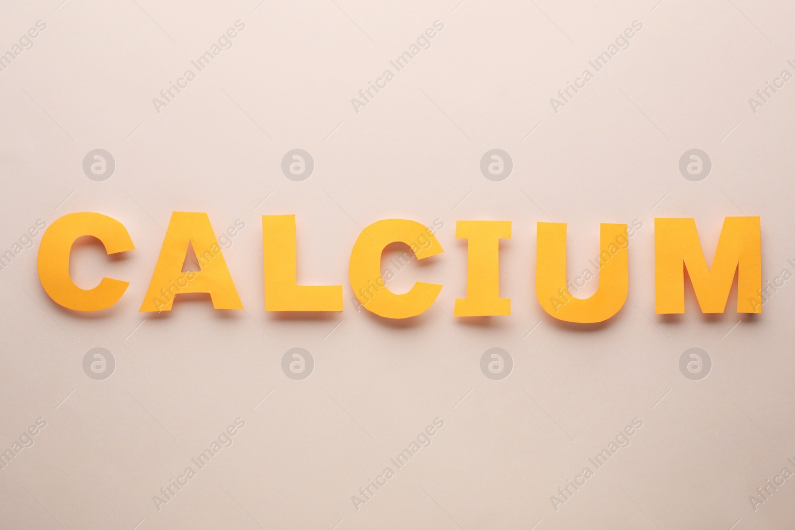 Photo of Word Calcium made of orange letters on beige background, flat lay