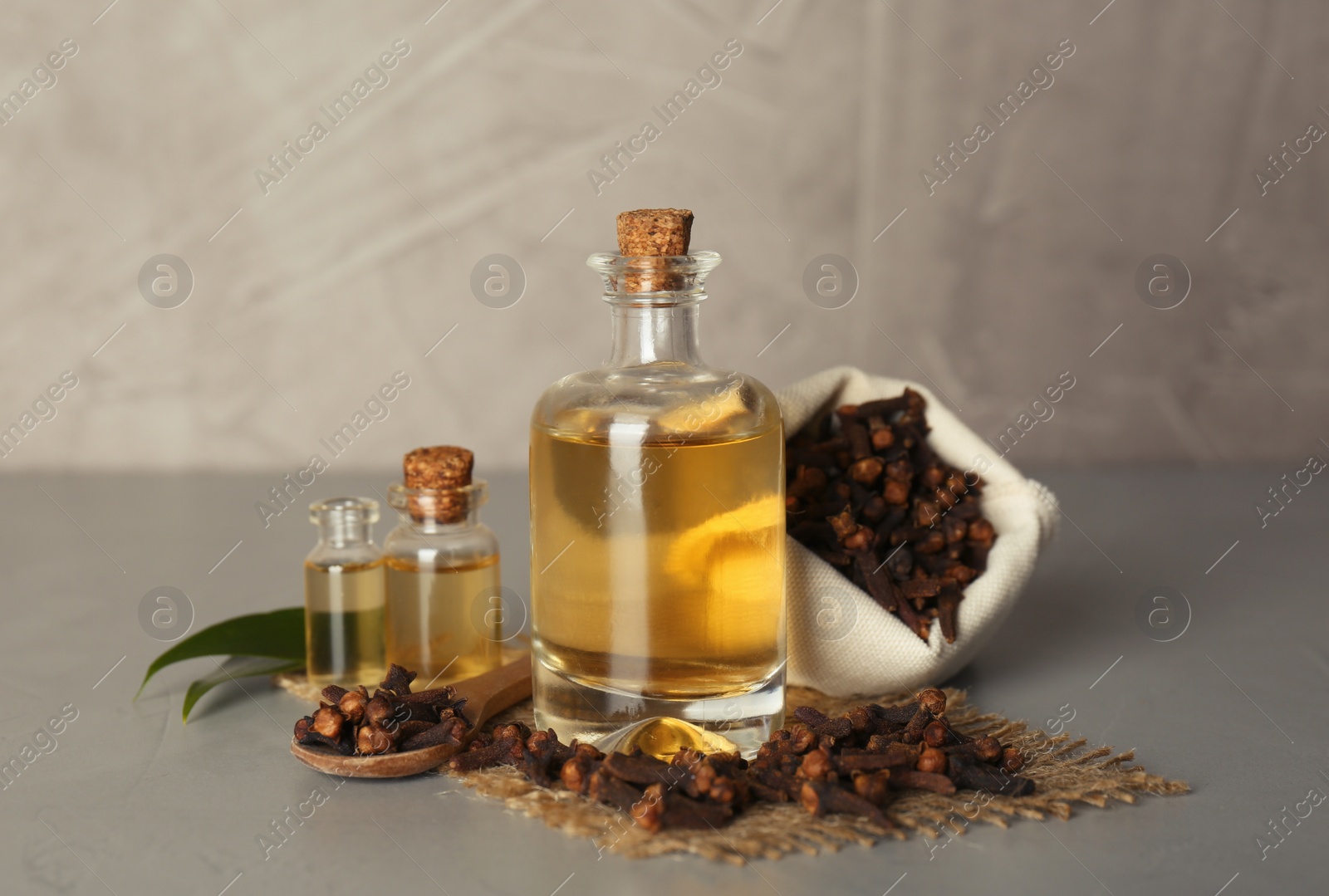 Photo of Essential oil and dried cloves on light grey stone table