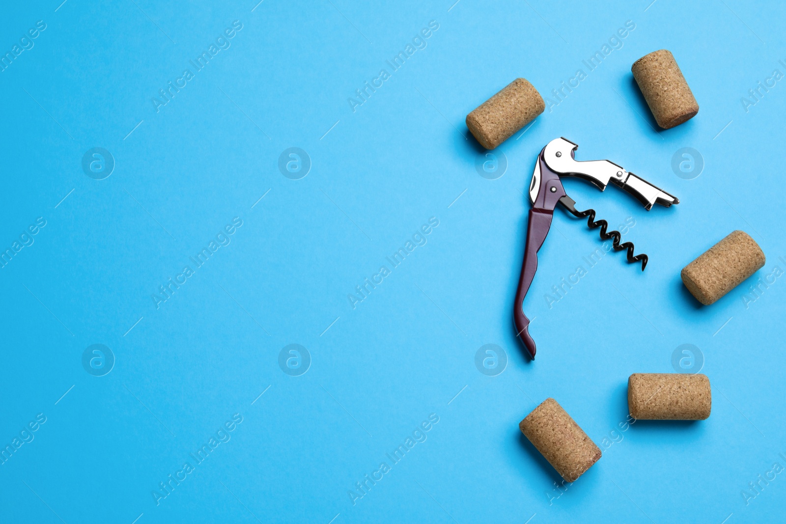 Photo of Corkscrew and wine bottle stoppers on turquoise background, flat lay. Space for text