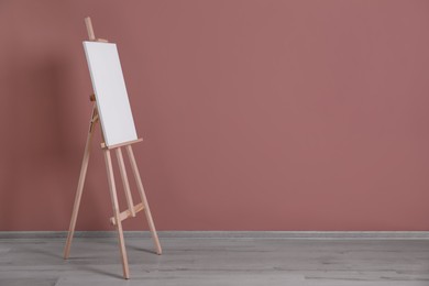 Photo of Wooden easel with blank canvas indoors. Space for text