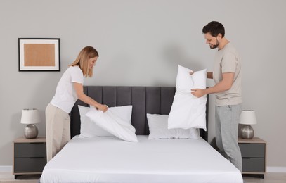 Couple changing bed linens in room. Domestic chores