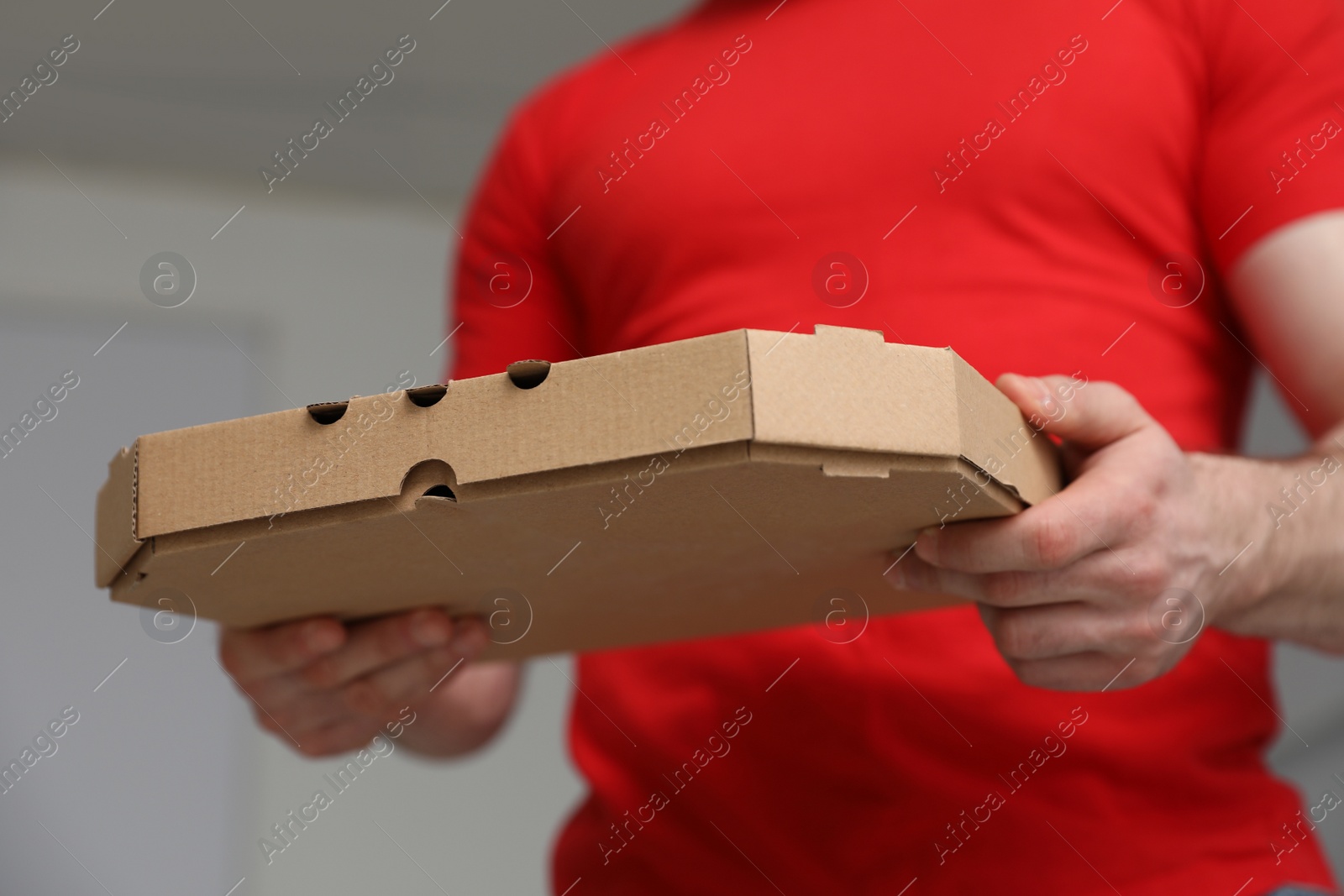 Photo of Courier with pizza box on blurred background, closeup