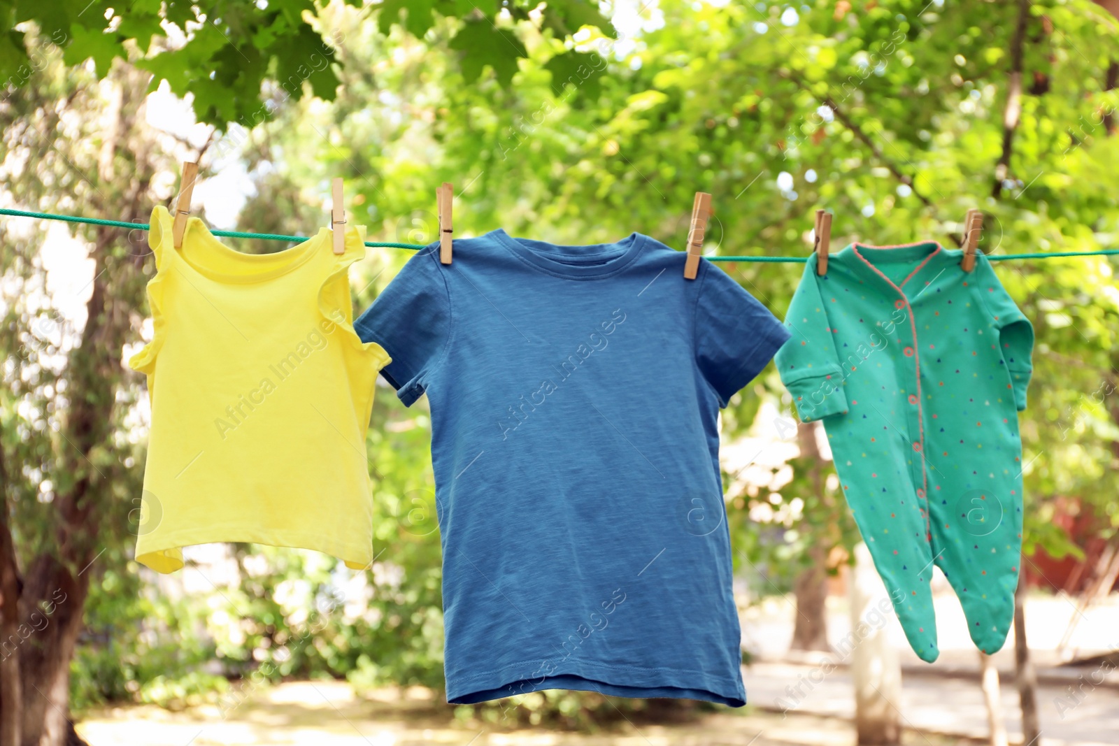 Photo of Laundry line with child's clothes outdoors on sunny day