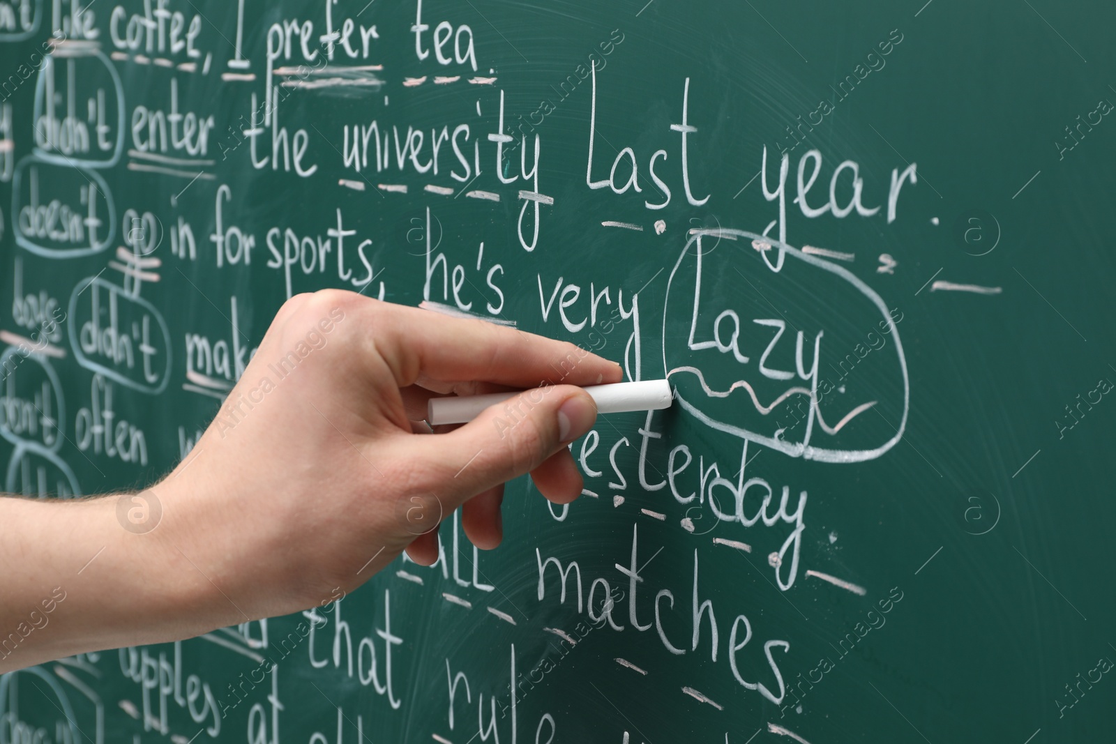 Photo of English teacher writing with chalk on green chalkboard, closeup