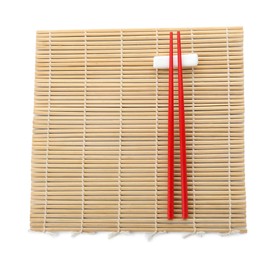 Photo of Bamboo mat with pair of red chopsticks and rest isolated on white, top view