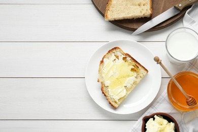 Photo of Glass with fresh milk, honey, butter and bread on white wooden table, flat lay. Space for text