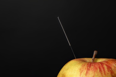 Needle for acupuncture and apple on dark background