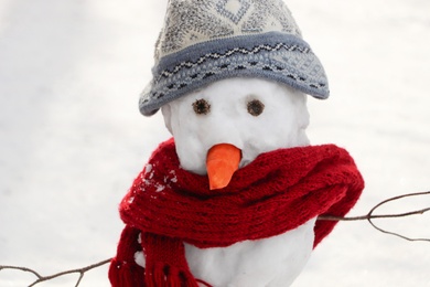 Funny snowman with scarf and hat outdoors, closeup