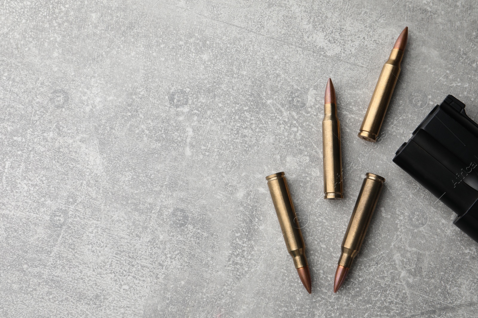 Photo of Bullets and handgun on light grey table, flat lay. Space for text