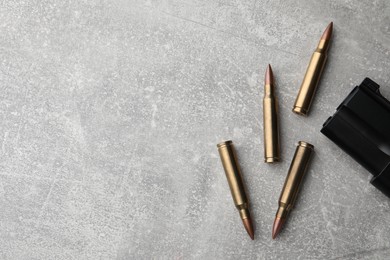 Photo of Bullets and handgun on light grey table, flat lay. Space for text