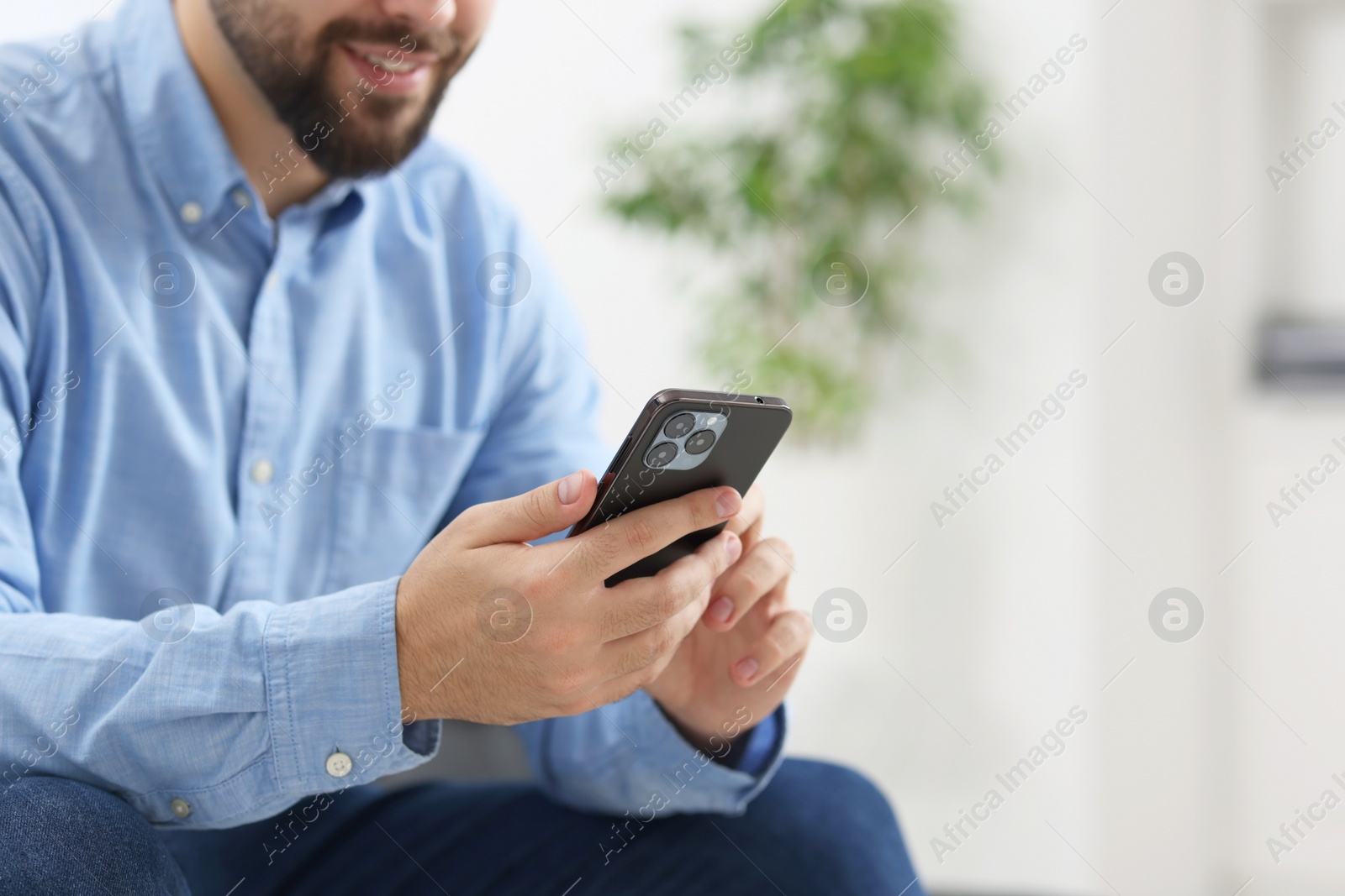 Photo of Young man using smartphone in office, closeup. Space for text