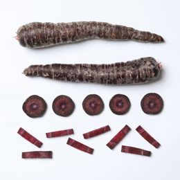 Photo of Whole and cut raw purple carrots on white background, top view