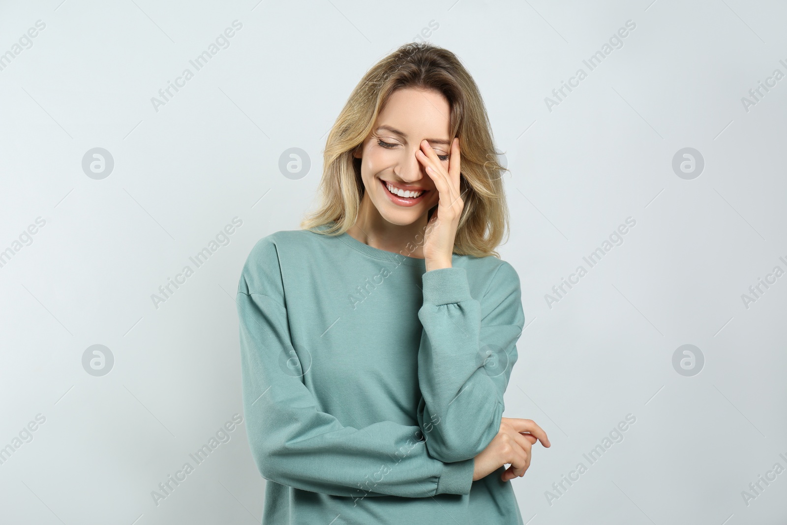 Photo of Portrait of happy young woman with beautiful blonde hair and charming smile on light background