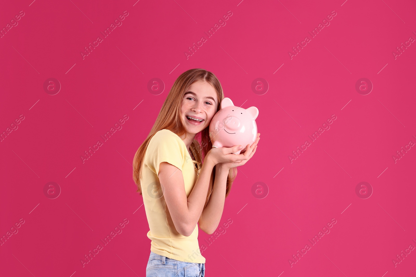 Photo of Teen girl with piggy bank on color background