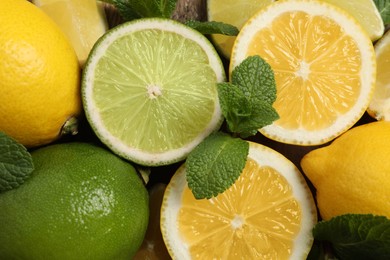 Photo of Fresh ripe lemons, limes and mint leaves as background, top view