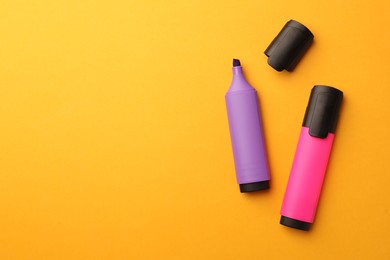 Bright markers on orange background, flat lay. Space for text