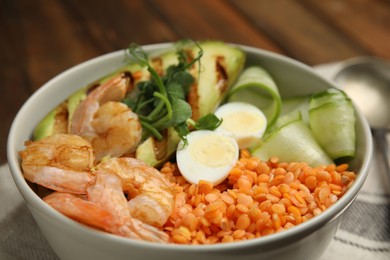 Photo of Delicious lentil bowl with avocado, shrimps, egg and cucumber on table, closeup