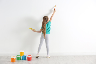 Little child painting on white wall indoors
