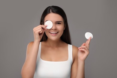 Young woman with cotton pads on grey background