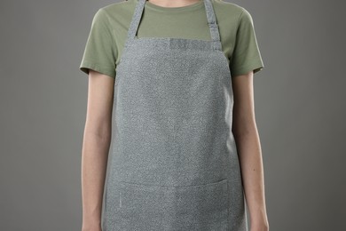 Woman wearing kitchen apron on grey background, closeup. Mockup for design