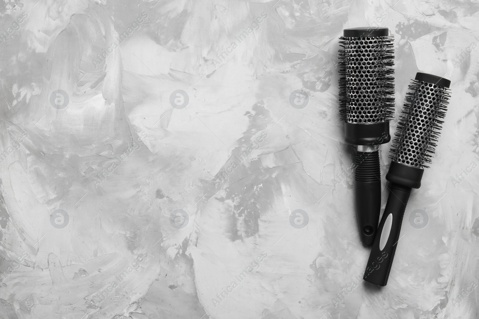 Photo of Hair brushes on light grey stone background, flat lay. Space for text