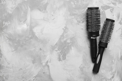 Hair brushes on light grey stone background, flat lay. Space for text