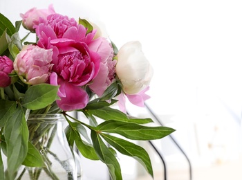 Photo of Vase with bouquet of beautiful peonies near white wall, space for text