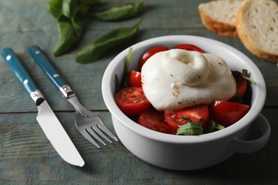 Delicious burrata cheese with tomatoes served on grey wooden table, closeup
