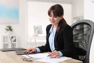 Photo of Smiling secretary working at table in office