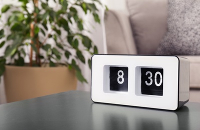 Photo of Modern flip clock on table in living room, space for text. Time of day