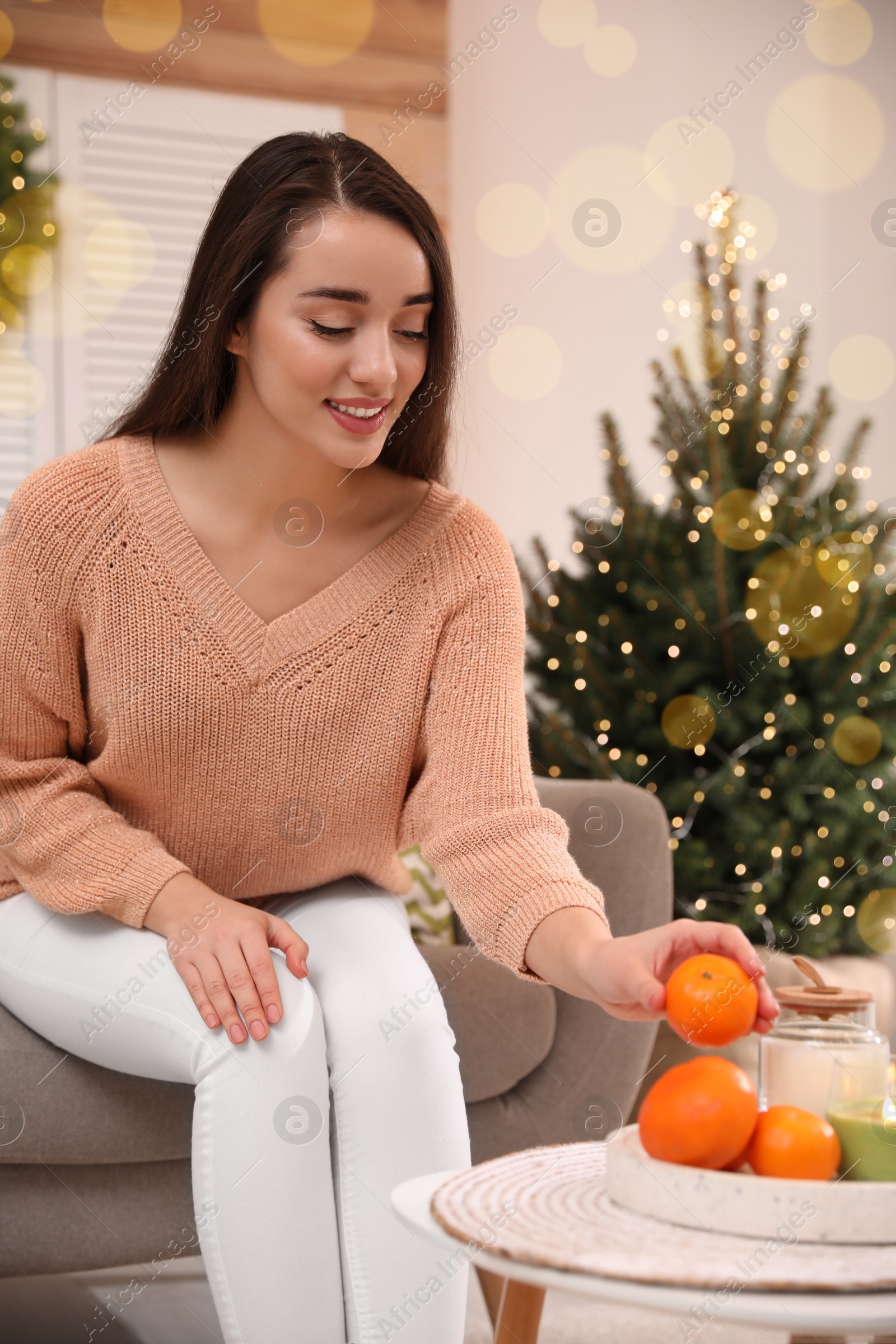 Photo of Happy young woman taking tangerine from table at home