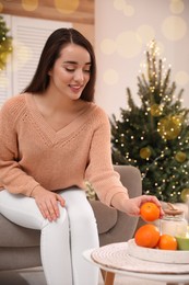 Photo of Happy young woman taking tangerine from table at home