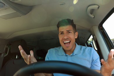 Photo of Stressed angry man in driver's seat of modern car, view through windshield