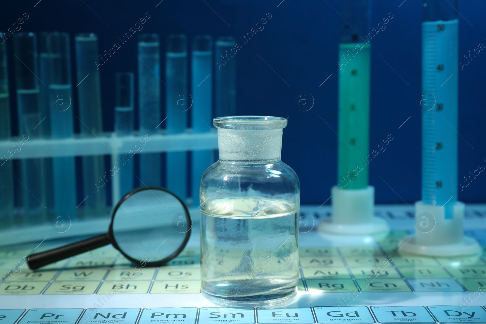 Photo of Magnifying glass and bottle on periodic table of chemical elements