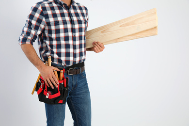 Photo of Carpenter with wooden planks on light background, closeup