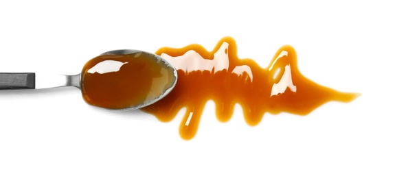 Photo of Spoon with delicious caramel sauce on white background