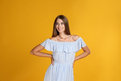 Photo of Young woman wearing stylish dress on yellow background