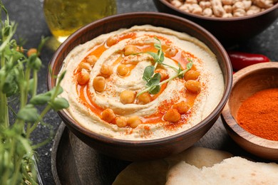 Photo of Delicious hummus with chickpeas and different ingredients on grey table