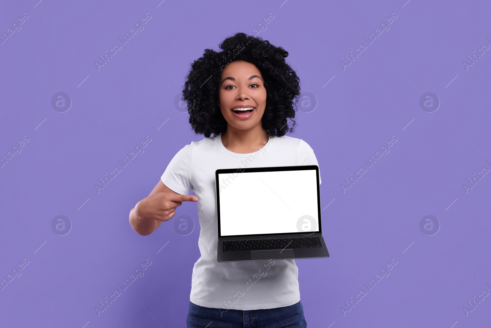 Photo of Happy young woman showing laptop on purple background