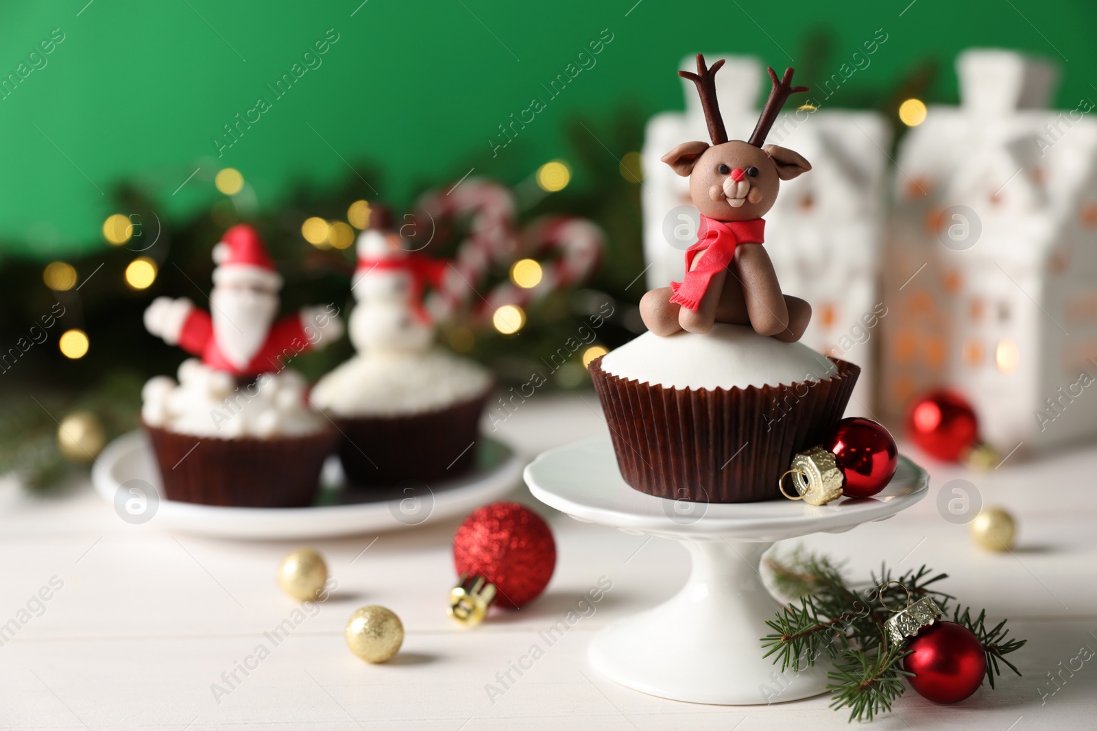 Photo of Tasty cupcake with Christmas reindeer figure on white wooden table. Space for text