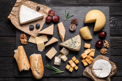 Photo of Flat lay composition with different types of delicious cheese on slate board