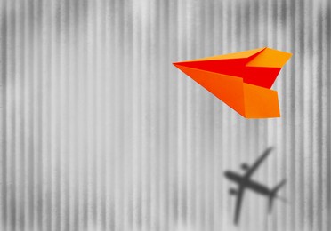 Image of Flying paper plane and shadow of a real airplane on light textured background