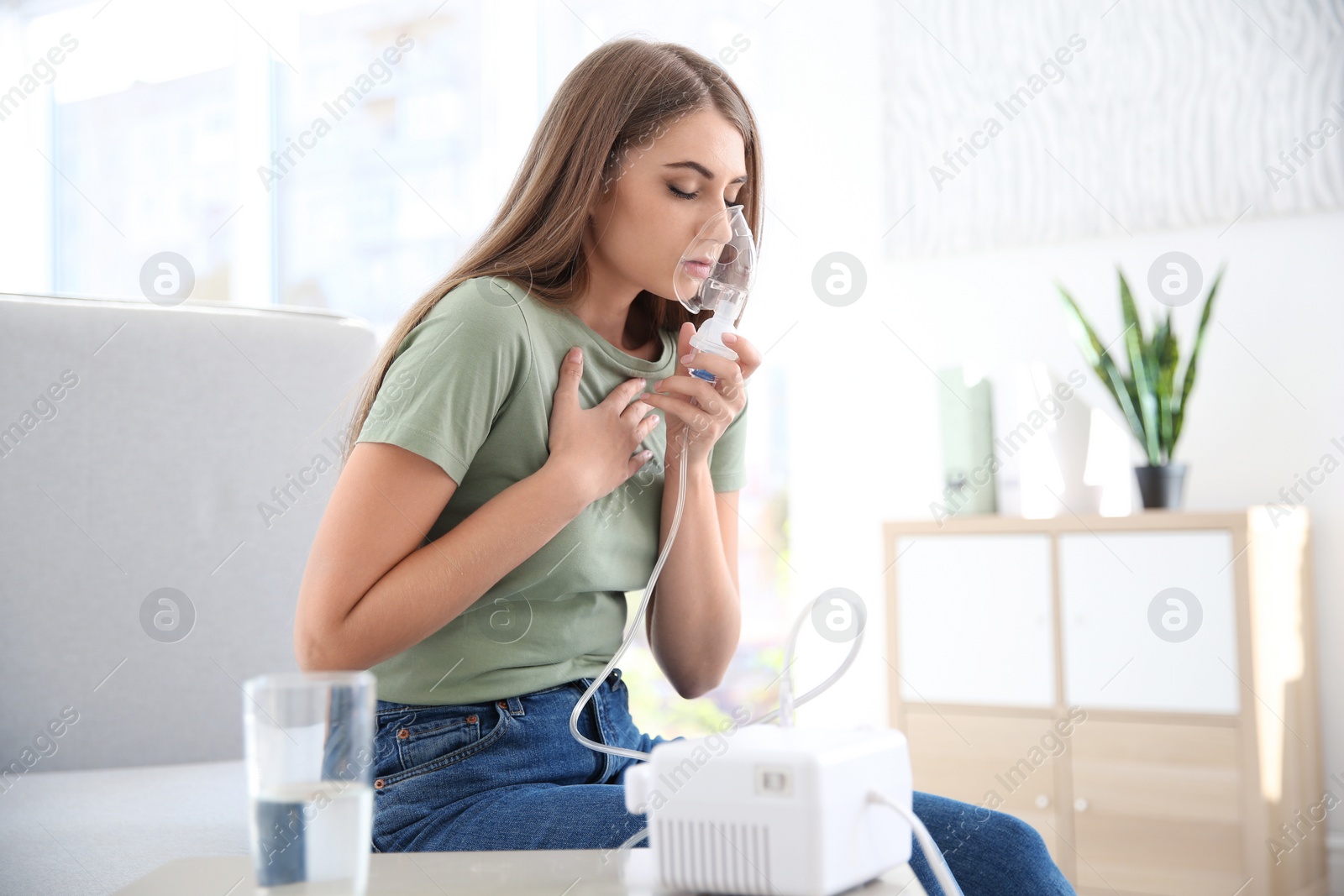 Photo of Young woman with asthma machine in light room