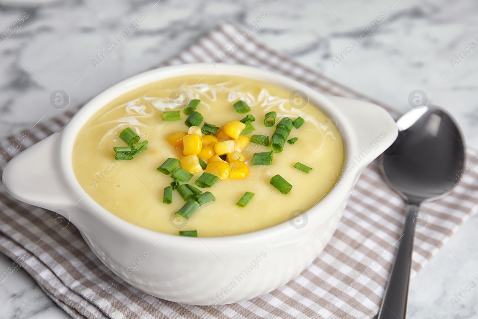 Photo of Delicious corn cream soup served on white marble table