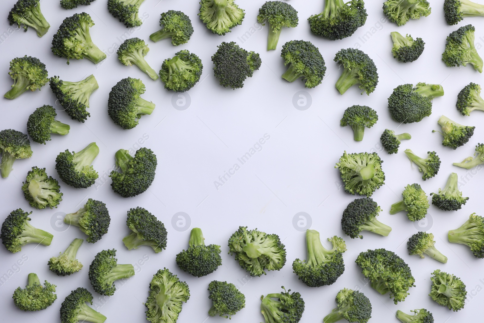 Photo of Frame made of many fresh green broccoli pieces on white background, flat lay. Space for text