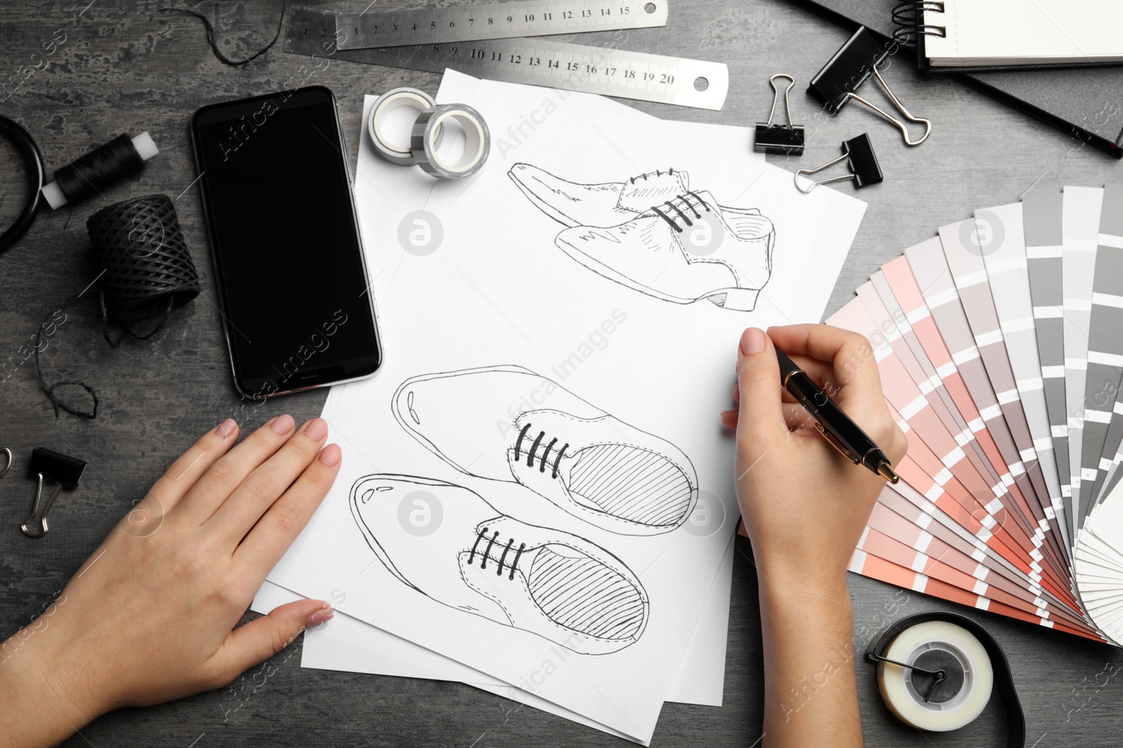 Photo of Fashion designer drawing shoes at grey table, top view