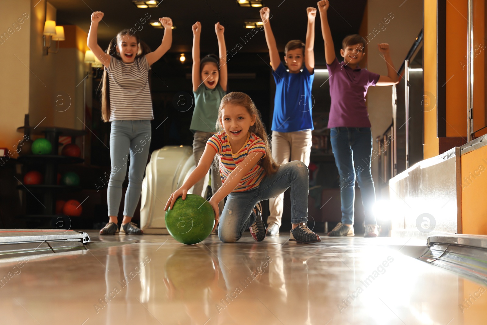 Photo of Girl throwing ball and spending time with friends in bowling club