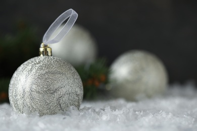 Beautiful Christmas ball on snow against dark background. Space for text